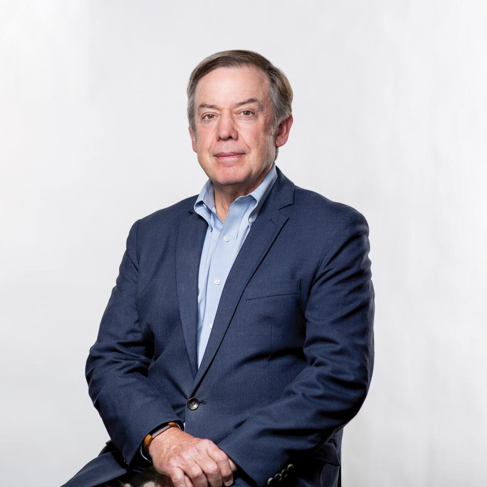 Photograph of Michael Crow, president of ASU, in a navy blue suit and light blue shirt