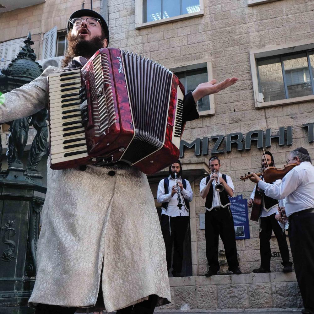 klezmer musician playing the accordion with band in the background