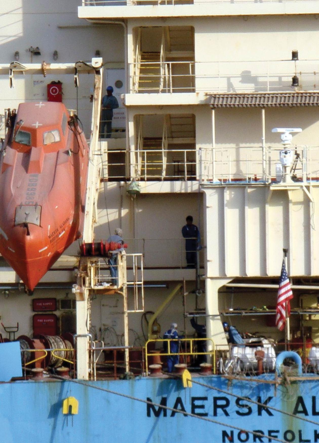 Photograph of a boat lowering a submarine into water