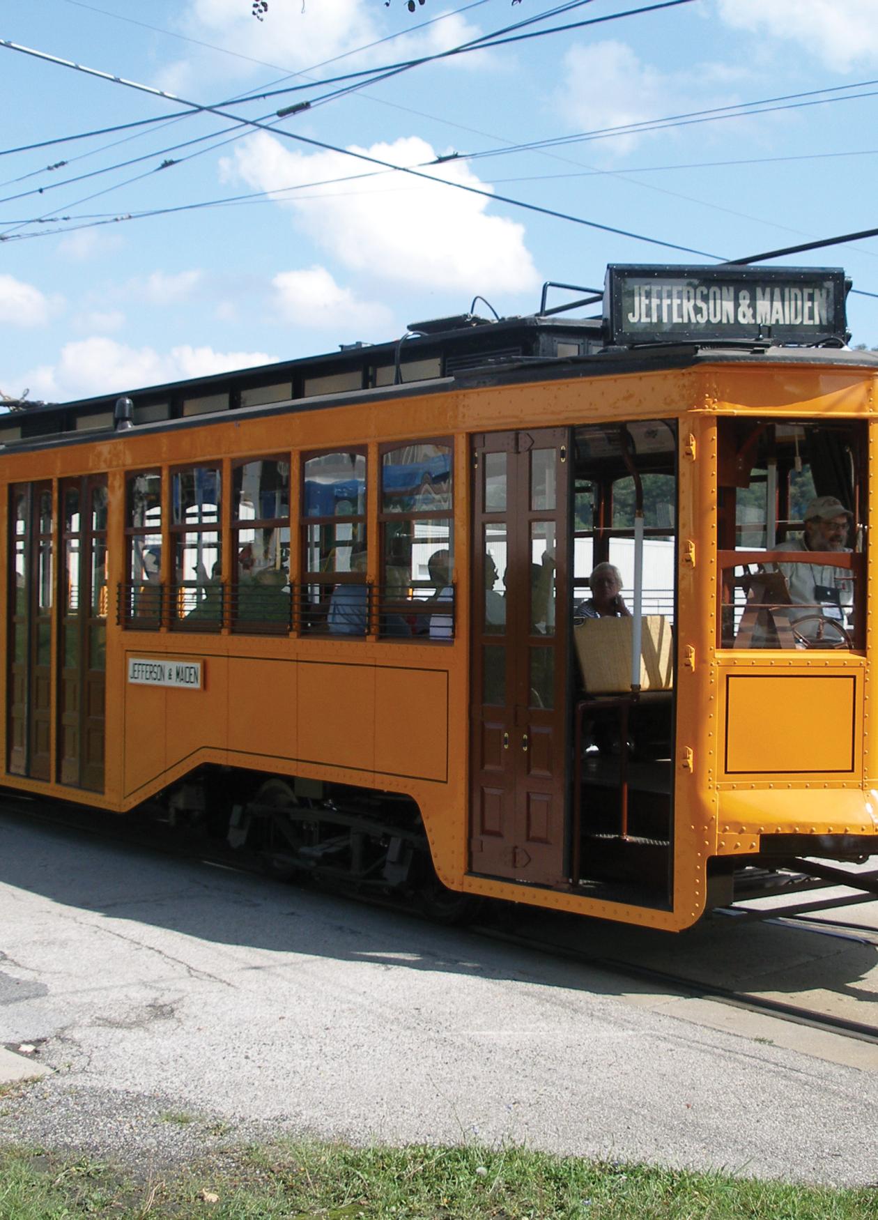 Color photo of a yellow trolley making its way.