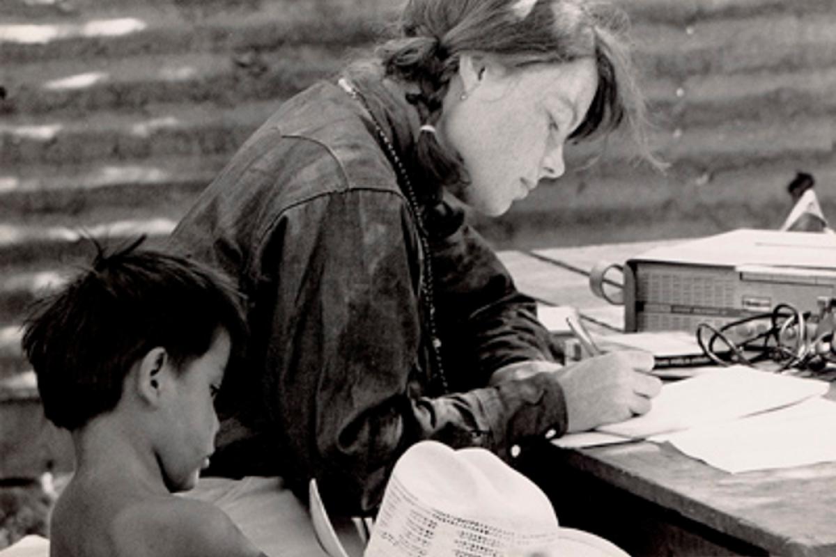 Woman writing on paper with a child next to her