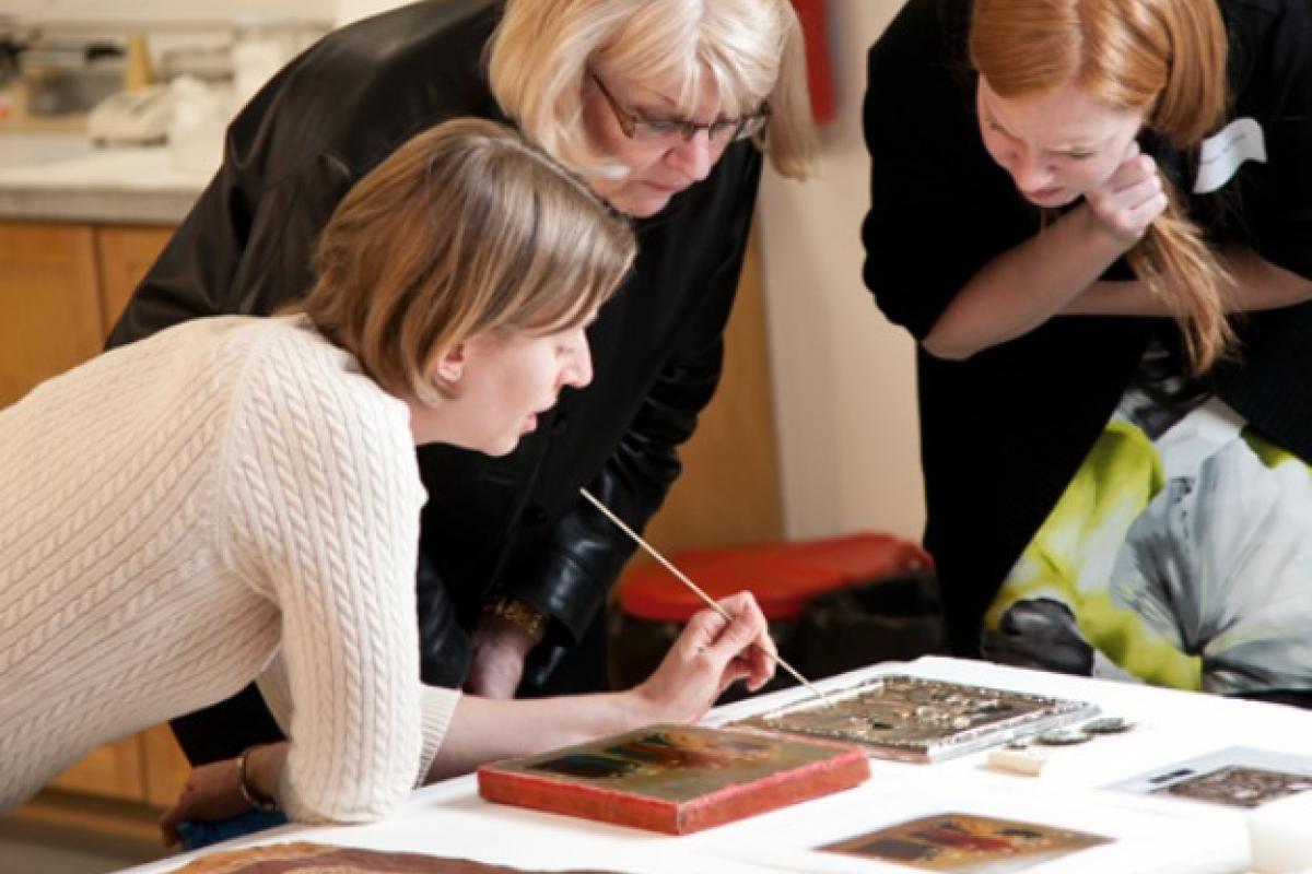 Three women bent over table looking at documents