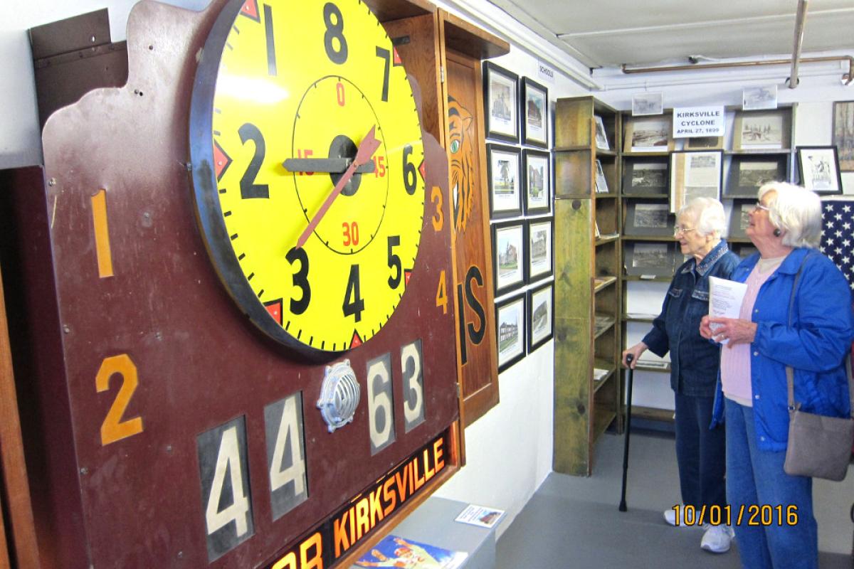 Two women viewing a vintage scoreboard