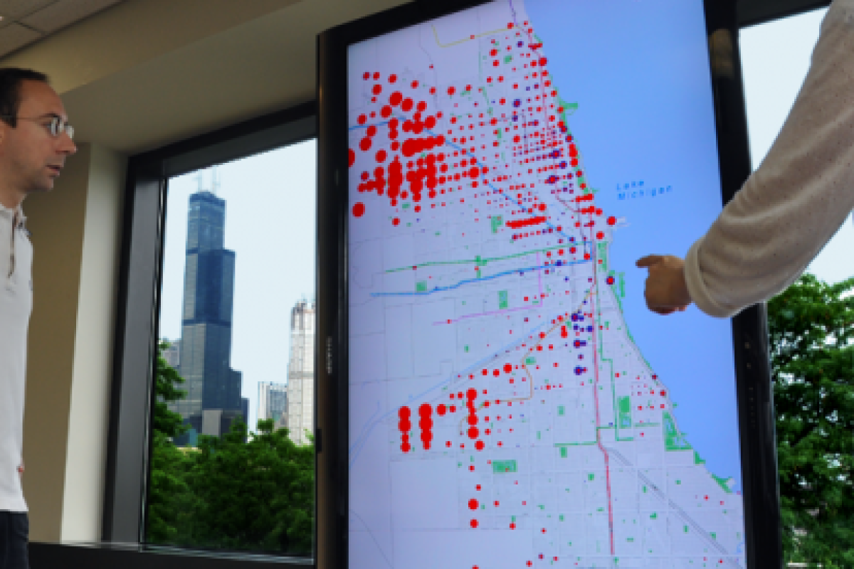 Large television display showing a map and scaled, colored dots which represent the relationships between different types of census data.