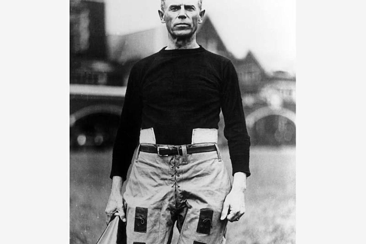 Black and white picture of man standing in black shirt and tan pants