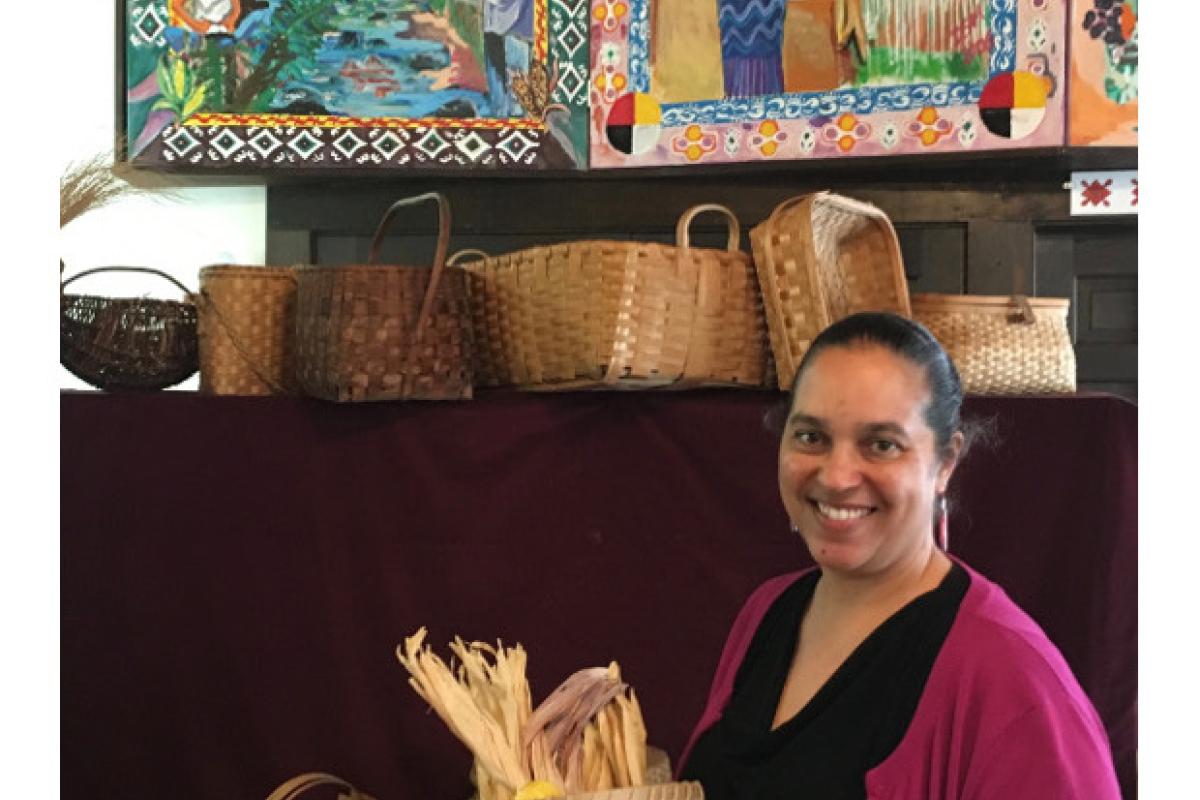 Interior view of museum with Lorén Spears holding corn washing basket made by Nuweetoon School students and artist David Little Tree.