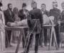 Sepia-colored image of doctors and other individuals working on a mummy that is laid out on a table.