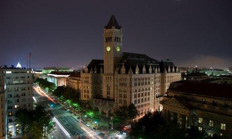 Photo of a building with several stories and a bell tower / clock, at night