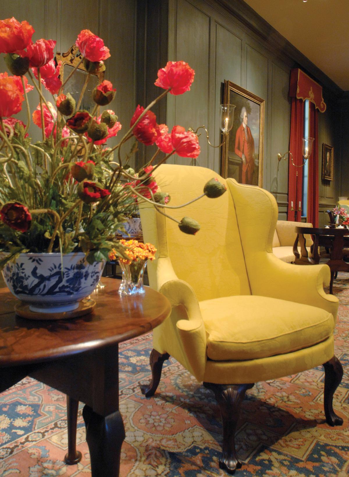 Photograph of a yellow chair with a bouquet of red flowers next to it