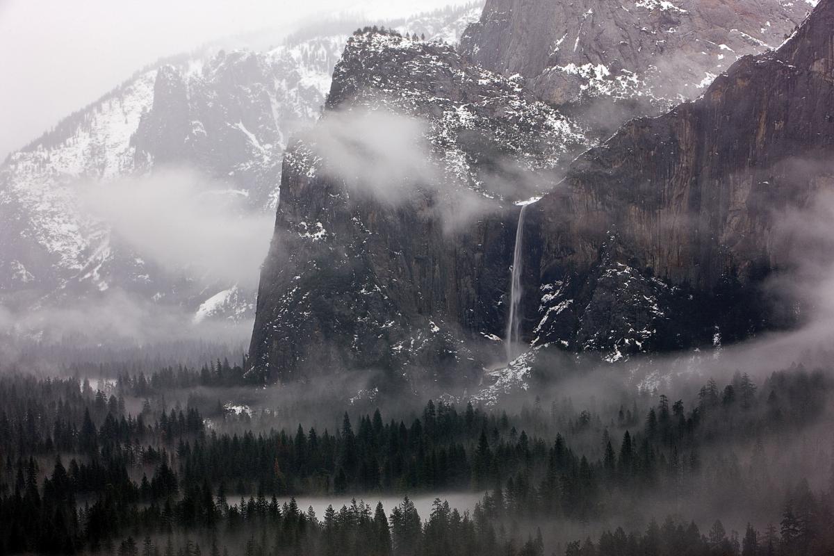 Far away photograph of Bridalveil Fall in a misty, snow dusted valley