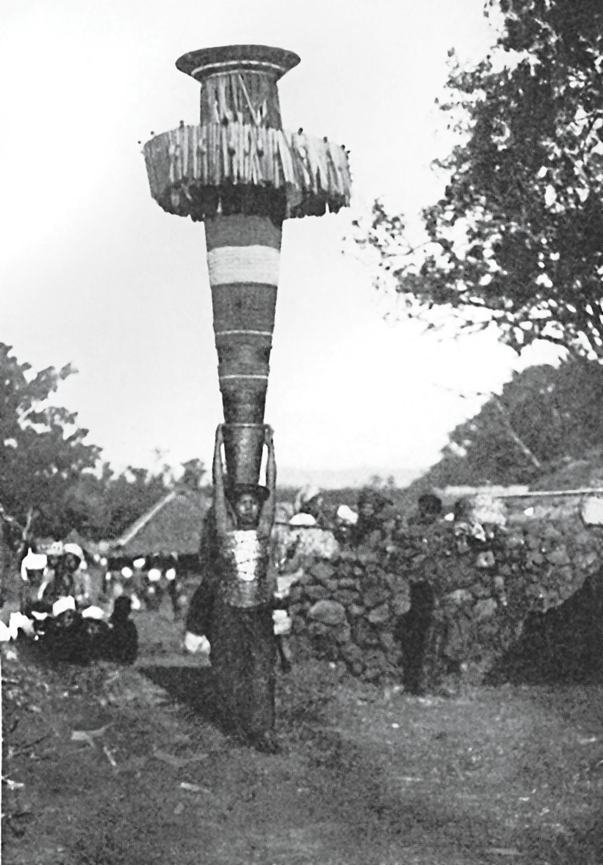 Woman carrying a tower of pot-like objects on top of her head