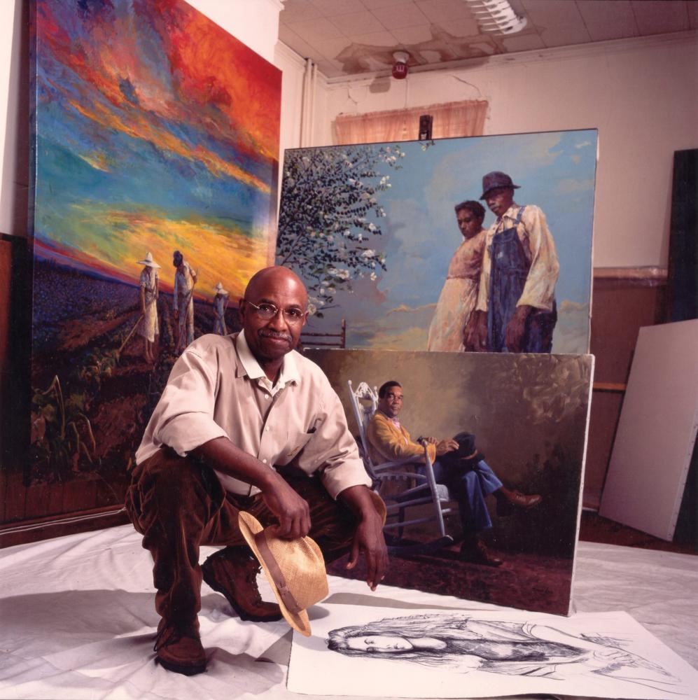 Color photo of Simmie Knox kneeling in his art studio.