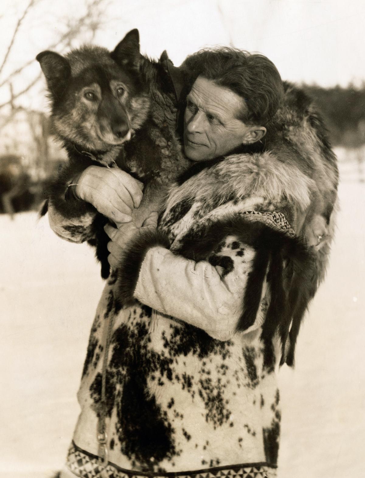 Black and white photo of a man with a dog on his shoulder