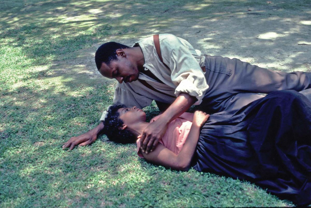 Solomon and Patsey lie on the grass in a tender embrace