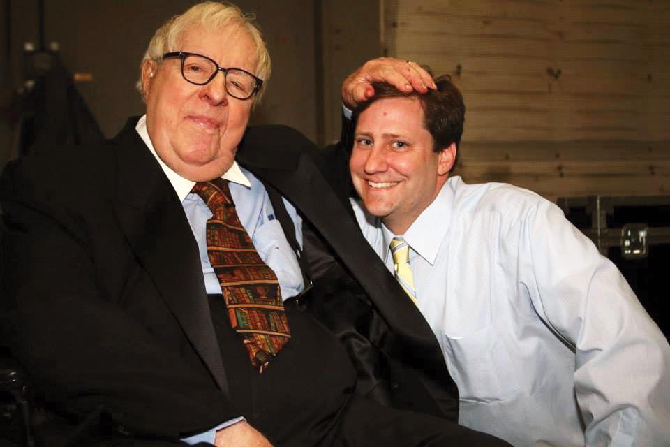 Photograph of two men, one has his hand on the head of the other