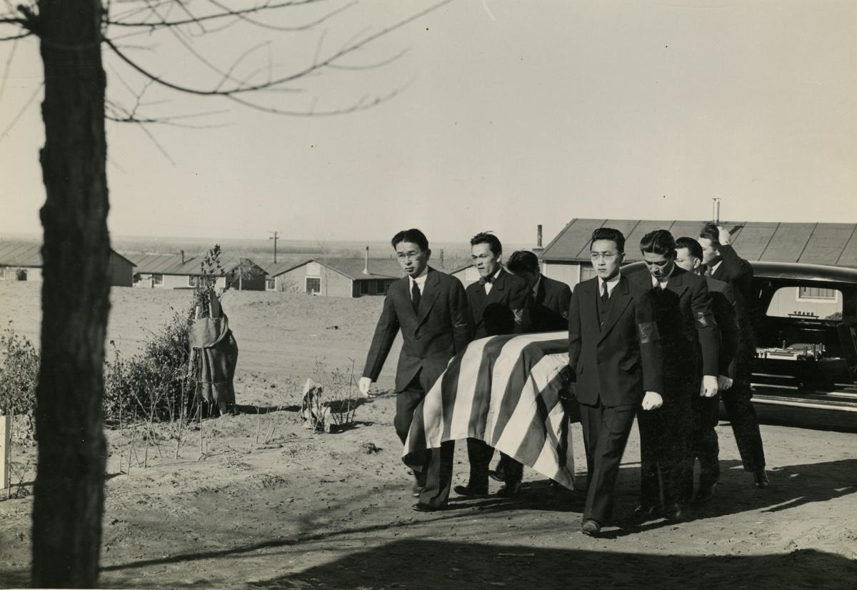 black and white photo of Japanese American men carrying a flag draped coffin