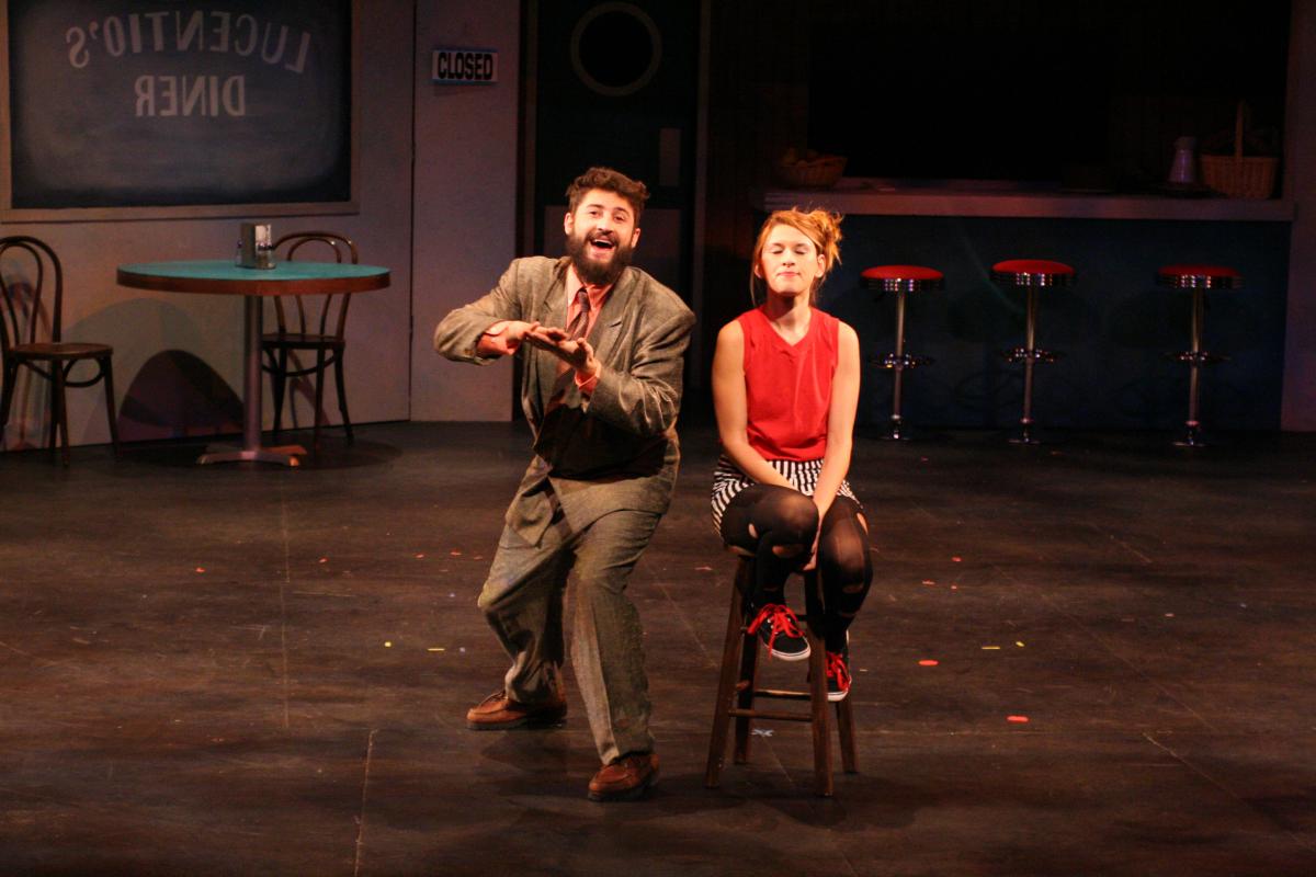 Two Deaf actors, left male and right female, are center stage performing in modern dress in The Taming of the Shrew.
