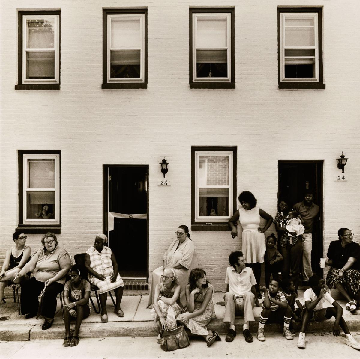 black and white photograph of Baltimoreans on stoop, watching a ribbon cutting