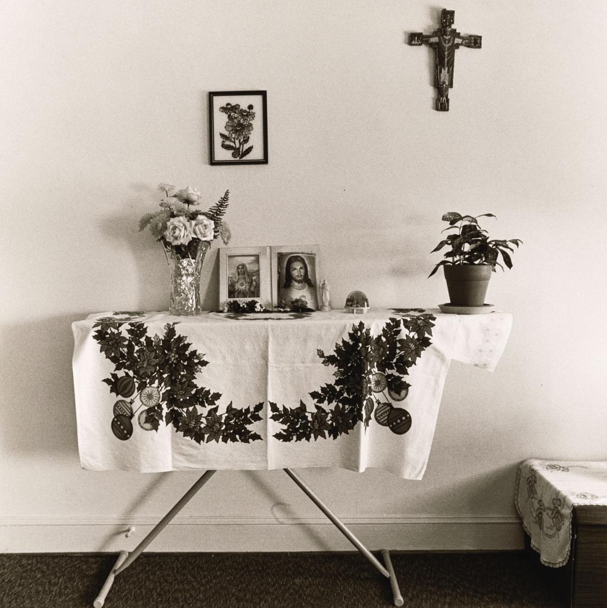 black and white photo of ironing board as an altar in someone's home