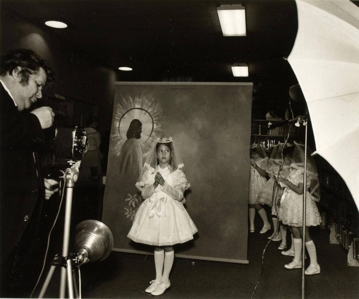 black and white photo of a young girl in white dress for first communion