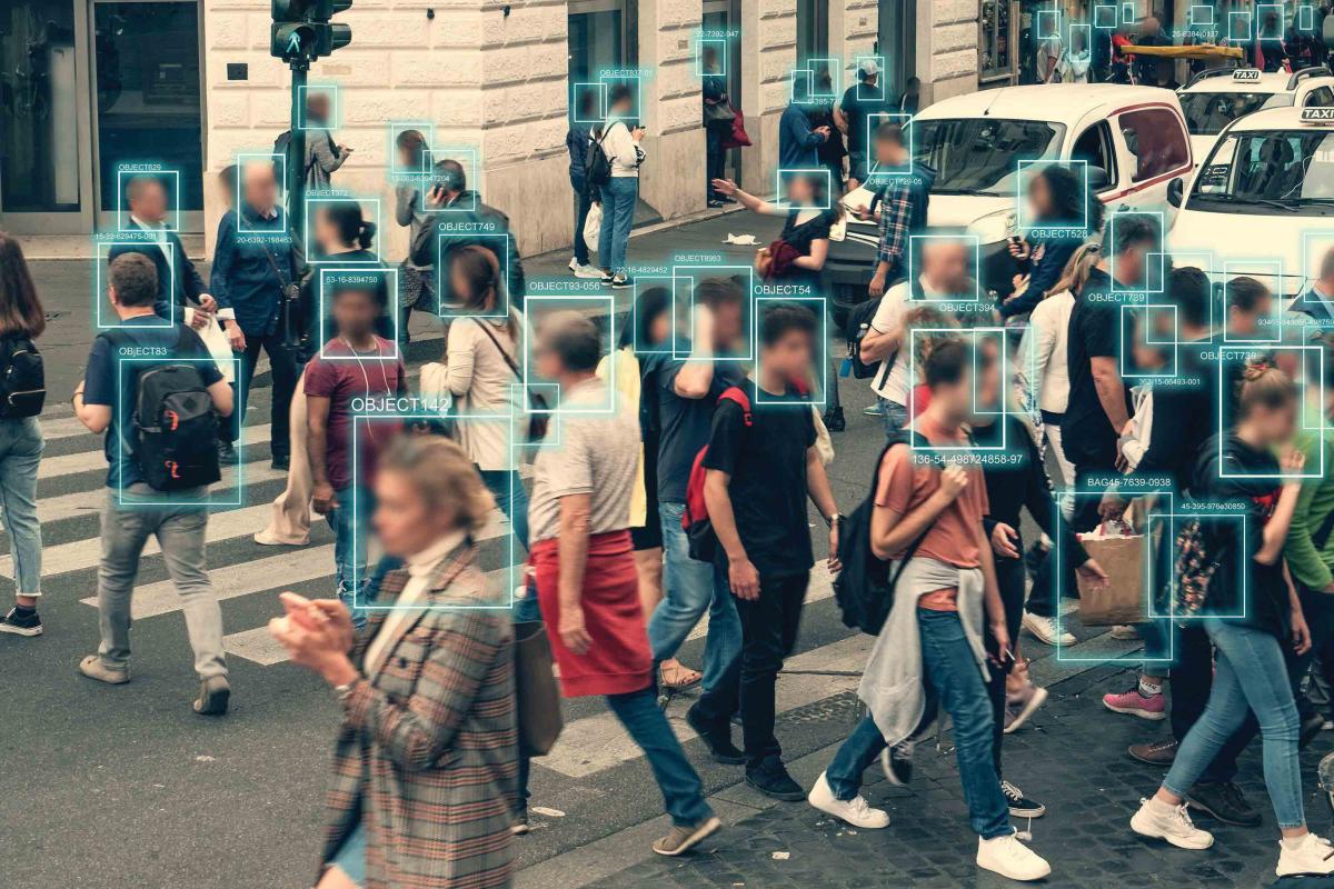 A group of people are crossing the street with coded numbers over each of their faces