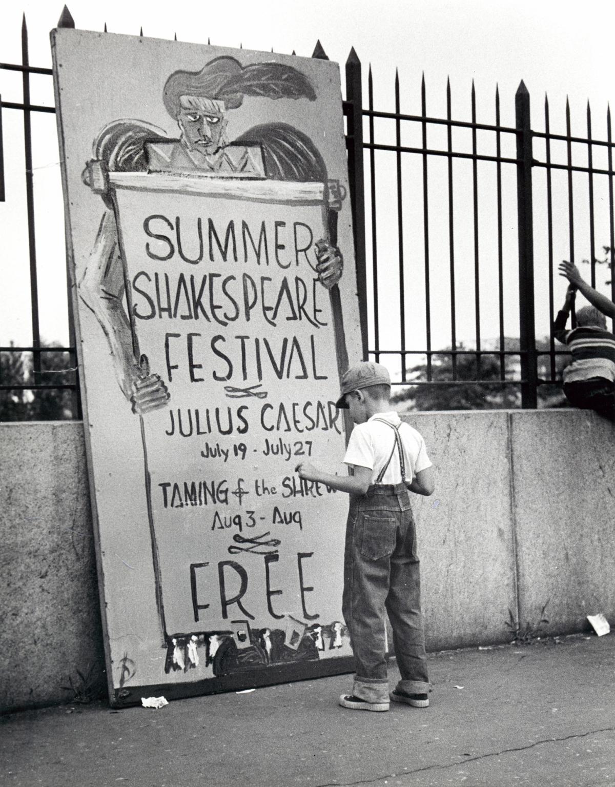 black and white photo of a child looking at a hand-made poster for Shakespeare