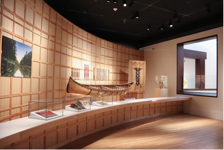 A birchbark canoe displayed near textiles and other objects.