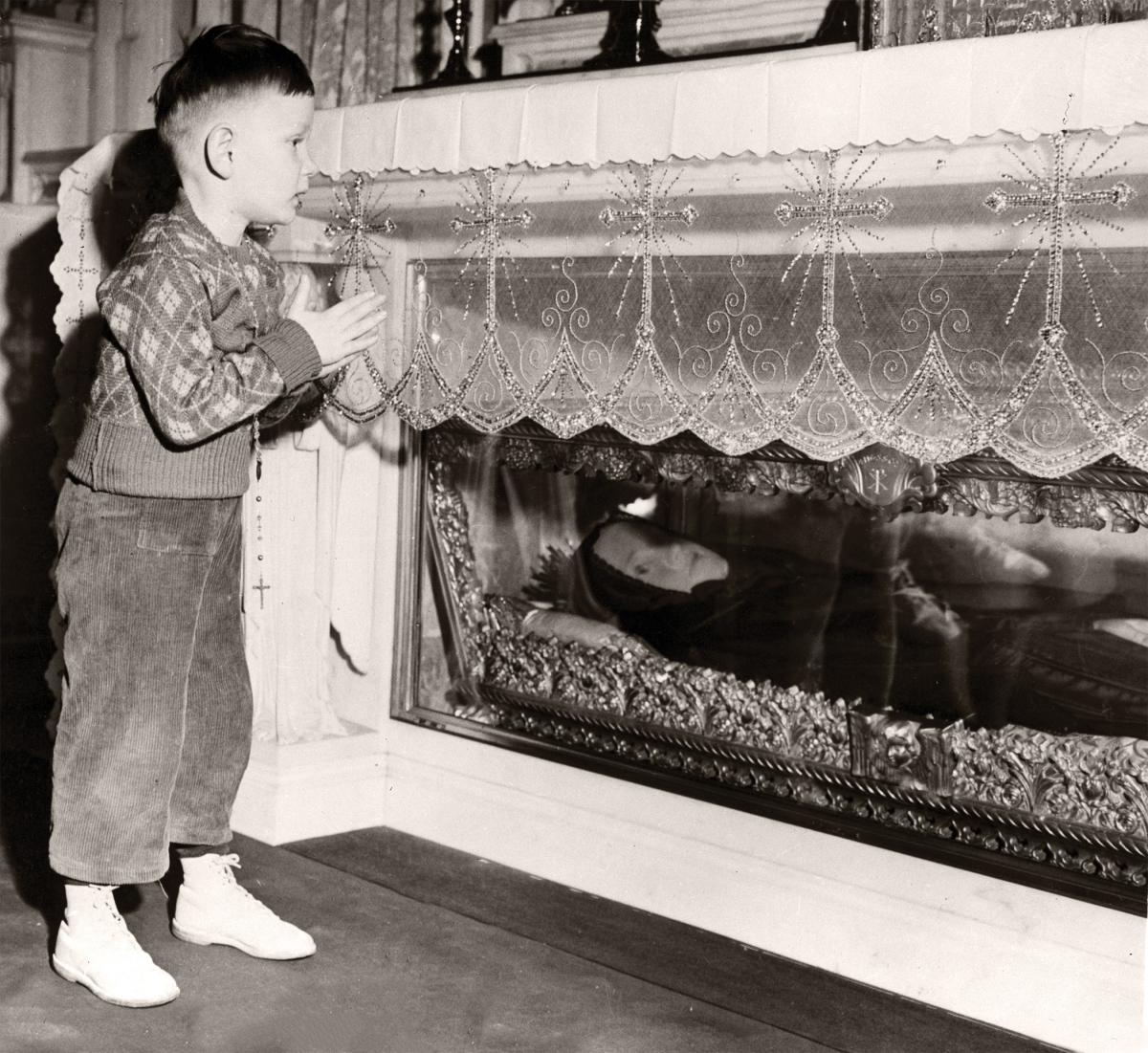Photo of a young boy standing by a shrine of Cabrini