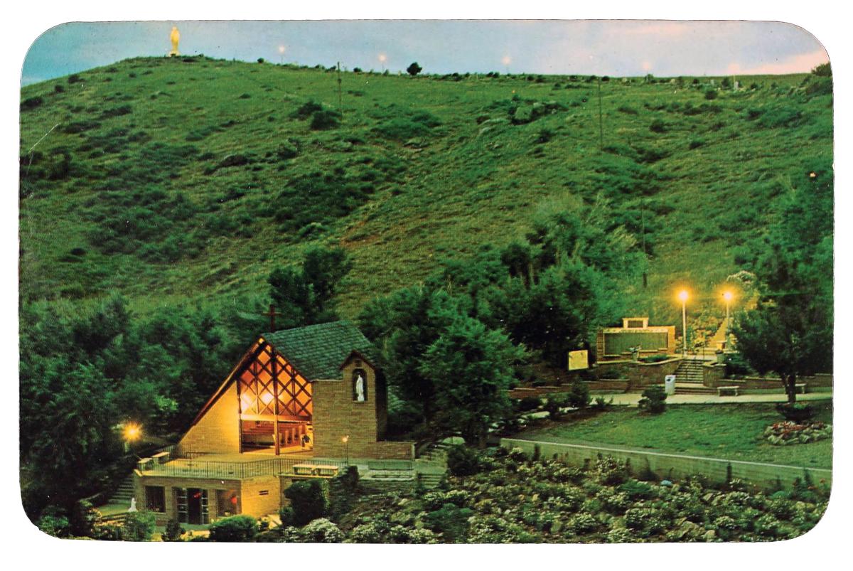 Green hillside depicting the Statue of the Sacred Heart in the distance