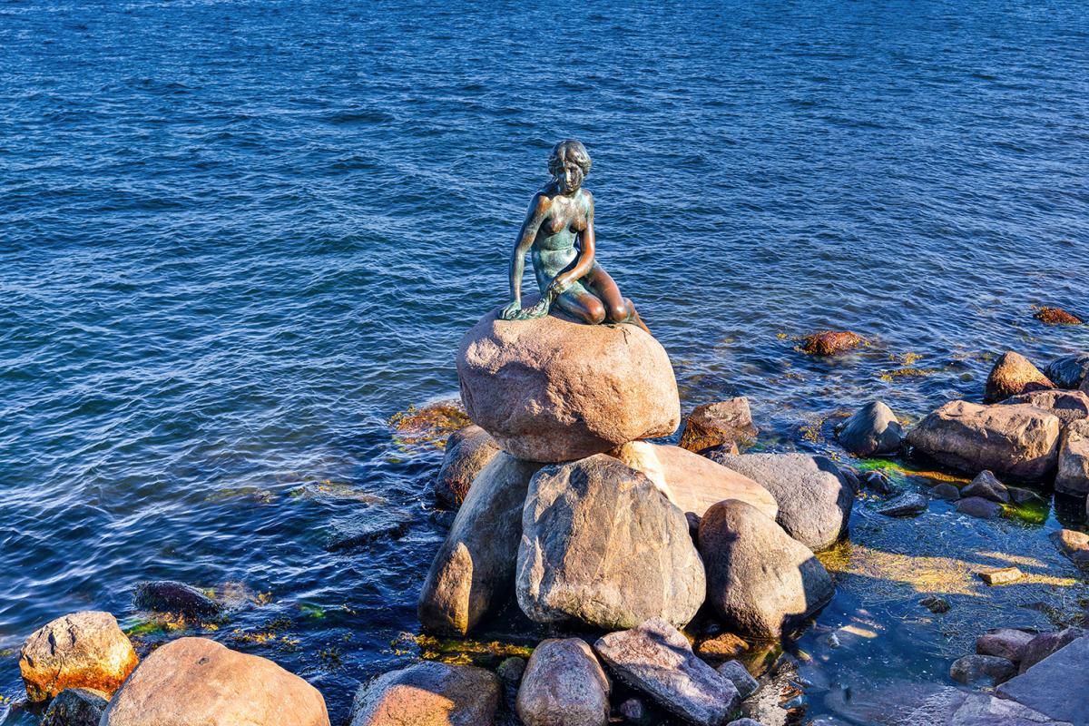 Copenhagen, Denmark - June 28, 2018: The Little Mermaid (Danish: Den lille Havfrue) on a rock by the waterside at the Langelinie promenade. It is a bronze statue by Edvard Eriksen.