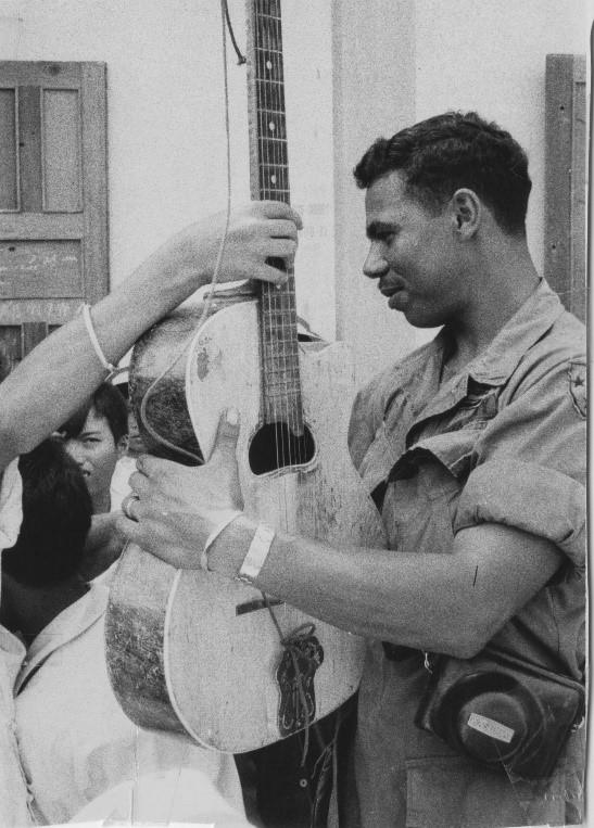 Accepting the guitar, Specialist Four Weston consents to sing a few American songs. Specialist Weston was on an American division MEDCAP mission with the 2nd Battalion of the 1st Infantry, 196th Brigade.