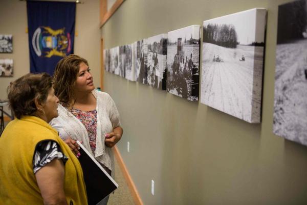 Two women looking at black and white photos on wall