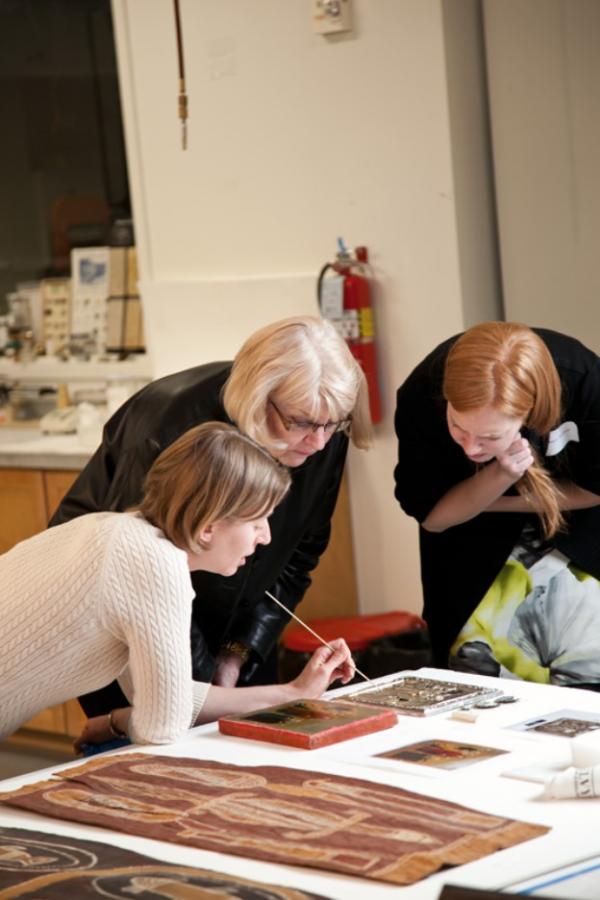 Three women bent over table looking at documents