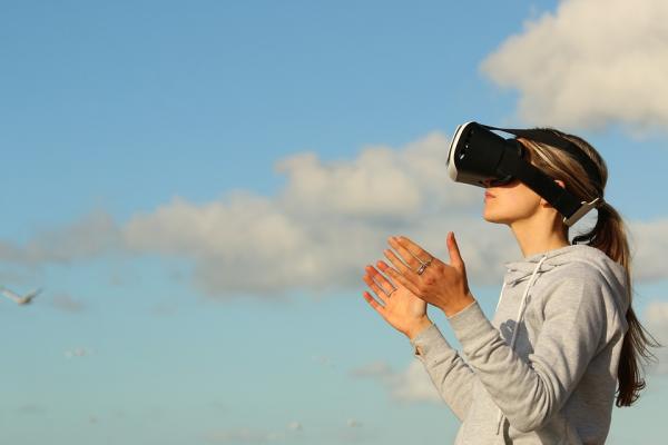 Woman wearing virtual reality glasses looking at the clouds