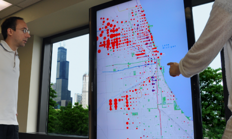 Large television display showing a map and scaled, colored dots which represent the relationships between different types of census data.