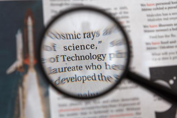 Magnifying glass over a dictionary page, focusing in on "science" and "technology"