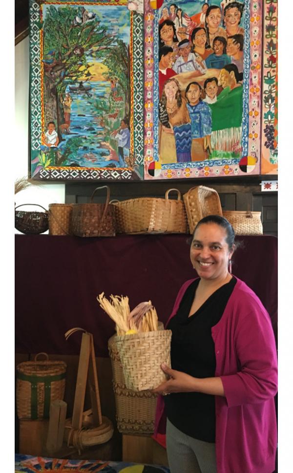 Interior view of museum with Lorén Spears holding corn washing basket made by Nuweetoon School students and artist David Little Tree.