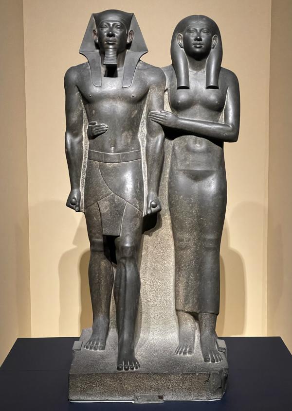 Egyptian statue of two figures in museum setting