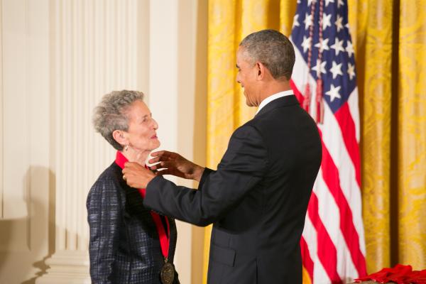 President Barack Obama places a red-ribboned medal on the neck of Natalie Zemon Davis.