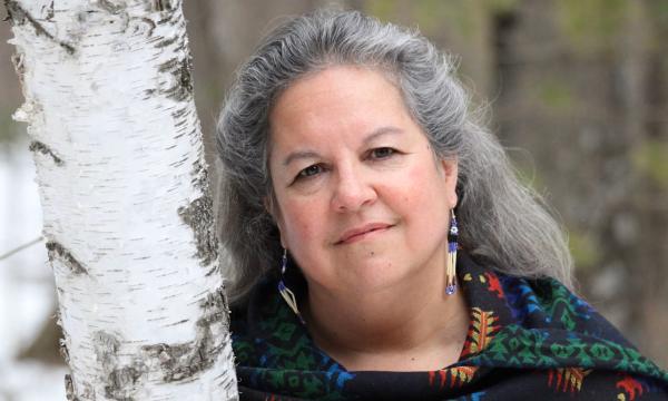 Photo of Robin Wall Kimmerer leaning against a tree