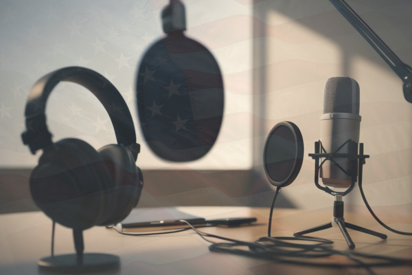 Podcasting equipment with a set of headphones and three microphones with a faint American flag overlay