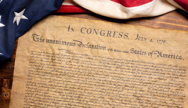 an aged copy of the Declaration of Independence flanked by an American flag at the top of the page