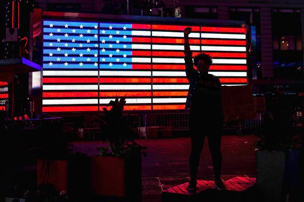 statue of a woman silhouetted against a glowing American flag