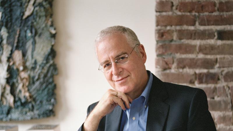 Ron Chernow, seated, with a book in his lap