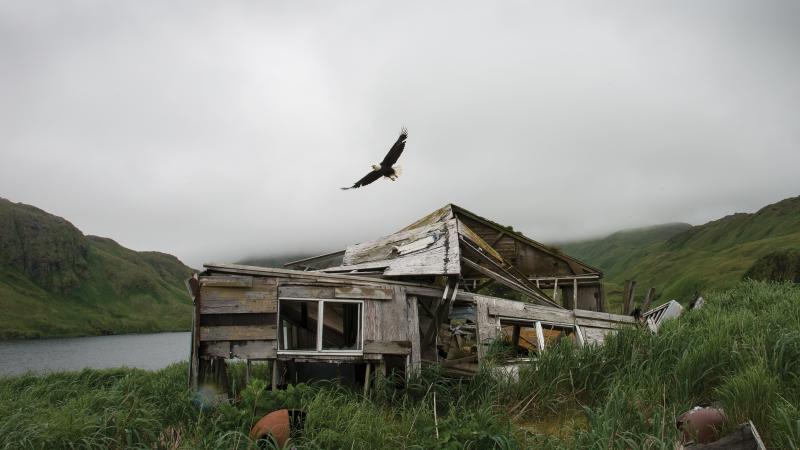 Photograph of cloudy sky in background, destroyed house in foreground