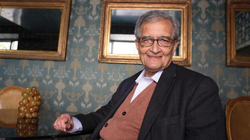 A photo of economist Amartya Sen sitting in a living room.