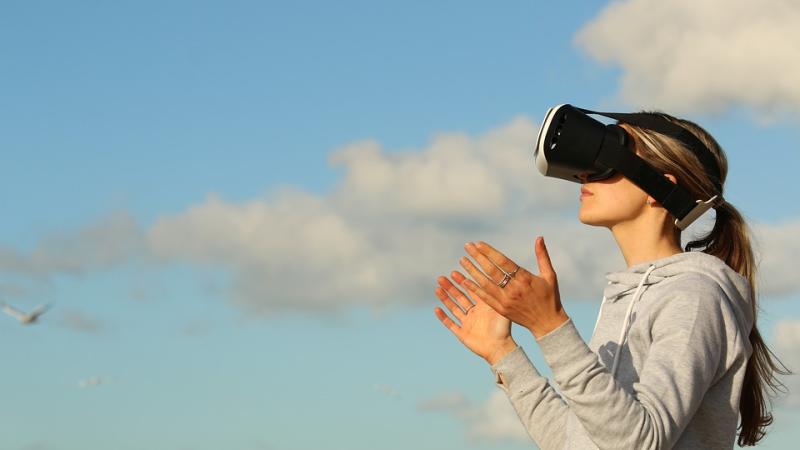Woman wearing virtual reality glasses looking at the clouds
