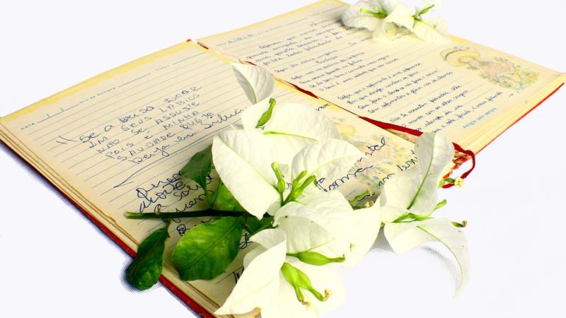 Photo of an open book of poetry, with a bunch of lilies laid on top of the book