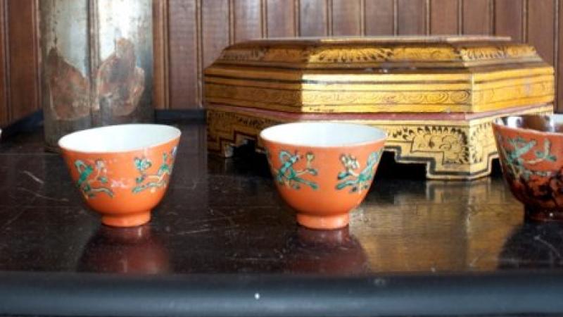 Two Asian-looking teacups on a table with a wood panel background
