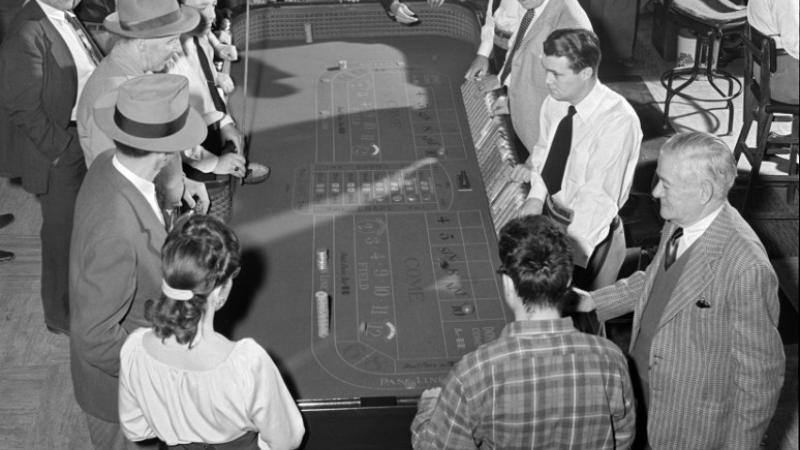 black and white photo of people gathered around a gaming table